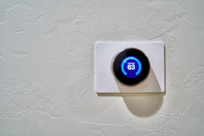 Room wall mounted thermostat displaying 63 degrees