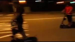 Blurred image of two men racing on electric scooters at night